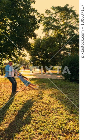 child father park, children game pilot sunset, kid flight, Spinning in the park at golden hour, Child flying with happiness, Capturing sweet family moments, Dad and daughter adventure, Sun rays 130037117