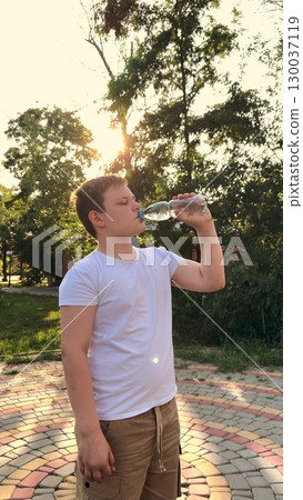 Thirsty after exercise, Cooling off in sunlight, Boy drinks and smiles, Fountain of youth, Natural refreshment, Routine hydration, Park and play, Sun setting behind, Active child, Pure water enjoyment Thirsty after exercise, Cooling off in sunlight, Boy drinks and smiles, Fountain of youth, Natural refreshment, Routine hydration, Park and play, Sun setting behind, Active child, Pure water enjoyment 130037119