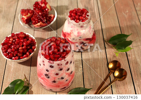 Fruit yogurt with pomegranate seeds and fresh cow cream for healthy nutrition in a glass on an elegant table. Healthy breakfast with ingredients, kitchen background 130037416