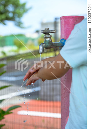 Kindergarten children washing their hands at a faucet in the park 130037994