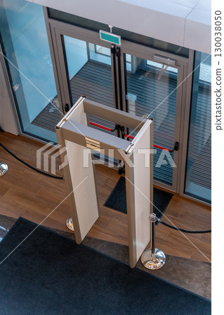 Automatic doors at a modern building entrance with a security metal detector scanner Automatic doors at a modern building entrance with a security metal detector scanner 130038050