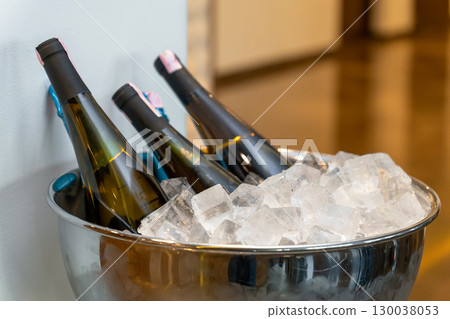 Elegant banquet setup with wine and champagne bottles chilling in a large ice bowl 130038053