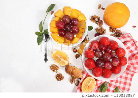 Useful breakfast, food for children, Strawberry yogurt, granola, cottage cheese, mango, strawberries and grapes on a light table. The concept of healthy and natural food. selective focus, top view 130038087