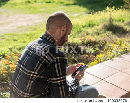 Young person using smartphone outdoors on sunny spring day Young person using smartphone outdoors on sunny spring day 130038378
