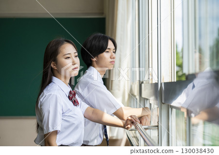 Male and female high school students looking out the classroom window Male and female high school students looking out the classroom window 130038430