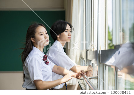 Male and female high school students looking out the classroom window Male and female high school students looking out the classroom window 130038431