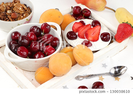 Fruit salad, Healthy breakfast with ingredients, yogurt with granola, strawberries, cherries and peaches on a light table. The concept of healthy and natural food, lifestyle. selective focus 130038610