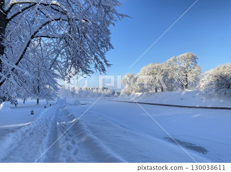 A picturesque winter landscape in Parnu, Estonia with a snow-covered path running along a riverbank 130038611