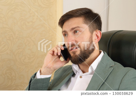 Businessman engaged in a phone call in a modern office setting during the day Businessman engaged in a phone call in a modern office setting during the day 130038629