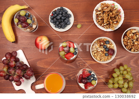 Useful breakfast with ingredients, flat lay, fruit salad with granola, grapes, bananas, strawberries and apple on a wooden table. The concept of losing weight, detox diet, lifestyle, top view Useful breakfast with ingredients, flat lay, fruit salad with granola, grapes, bananas, strawberries and apple on a wooden table. The concept of losing weight, detox diet, lifestyle, top view 130038692