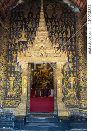 Wat XiengthongGolden Buddha statue inside ornate temple with visitors praying on red carpet Wat XiengthongGolden Buddha statue inside ornate temple with visitors praying on red carpet 130038821