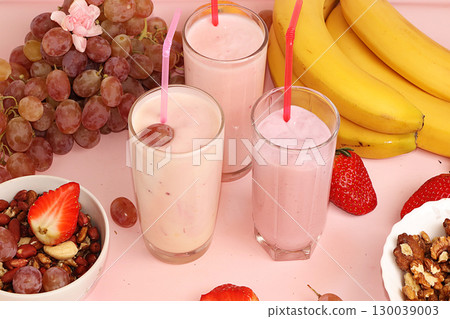Strawberry and banana smoothies, granola, fresh berries, bananas and grapes on a pink sunny background. The concept of healthy and natural food. Useful breakfast, 130039003