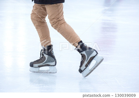 feet on the skates of a person rolling on the ice rink 130039009