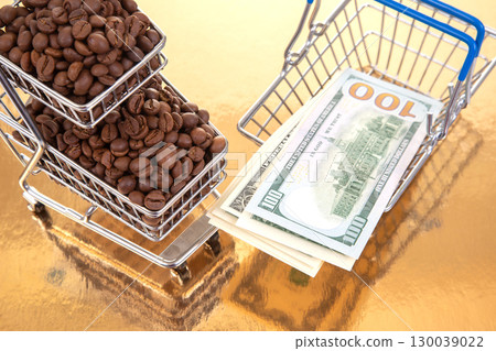 A tiny cart filled with coffee beans sits next to $100 bills on a golden table A tiny cart filled with coffee beans sits next to $100 bills on a golden table 130039022