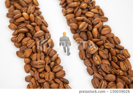 Unique stock photo featuring a small figurine in a suit walking through coffee beans 130039026
