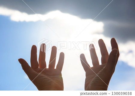 Silhouette raised hands against a bright sun and cloudy sky Silhouette raised hands against a bright sun and cloudy sky 130039038