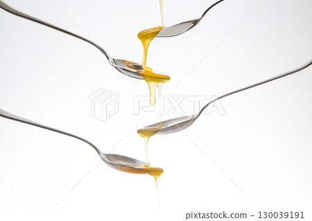 Fresh flower honey drips from a spoon into a spoon on a white background. Organic vitamin food. Fresh flower honey drips from a spoon into a spoon on a white background. Organic vitamin food. 130039191