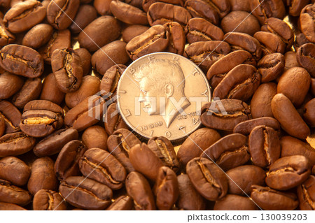 Roasted coffee beans with a U.S. dime for scale on a golden reflective background Roasted coffee beans with a U.S. dime for scale on a golden reflective background 130039203