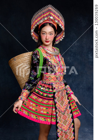 Beautiful Asian woman wearing traditional colorful ethnic costume and silver jewelry, posing in studio portrait. Cultural fashion photography showcasing vibrant embroidery, handmade textile. Beautiful Asian woman wearing traditional colorful ethnic costume and silver jewelry, posing in studio portrait. Cultural fashion photography showcasing vibrant embroidery, handmade textile. 130039269