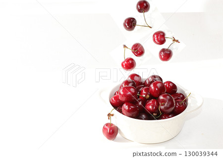 Cherry flying in a white cup on a light table. The concept of healthy and natural food, lifestyle. selective focus 130039344