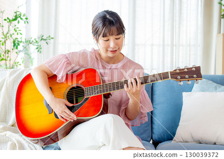 A young lady playing the guitar A young lady playing the guitar 130039372