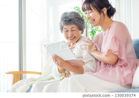 Young and senior women looking at a tablet Young and senior women looking at a tablet 130039374