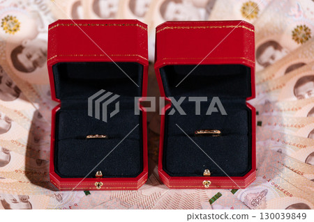 gold rings in red jewelry boxes on currency background for engagement or wedding 130039849