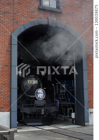 A steam locomotive entering a red brick engine shed A steam locomotive entering a red brick engine shed 130039875