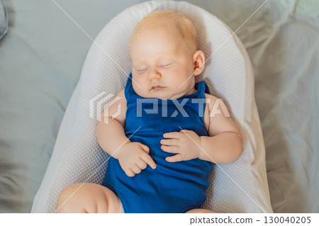 Chubby 3-month-old baby peacefully sleeping in a cozy baby nest at home. Concept of infant comfort, safety, and early development in a warm and nurturing environment 130040205