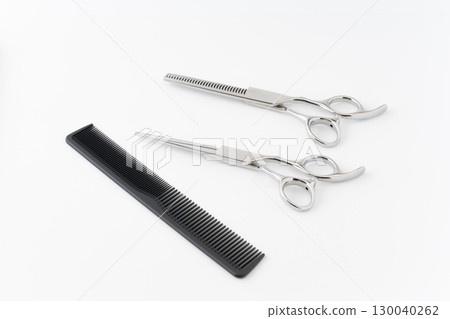 A set of haircutting scissors, thinning shears and a comb on a white background A set of haircutting scissors, thinning shears and a comb on a white background 130040262