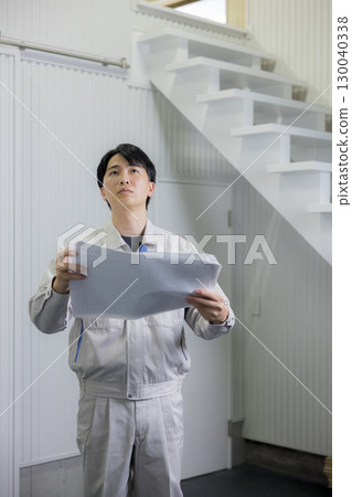 一名身穿工作服的男子正在查看倉庫裡的藍圖 130040338