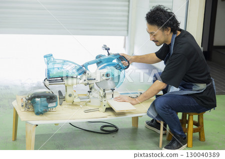 Craftsman working with an electric circular saw 130040389