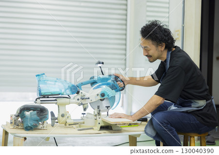 Craftsman working with an electric circular saw Craftsman working with an electric circular saw 130040390