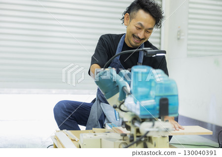 Craftsman working with an electric circular saw 130040391