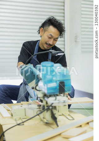 Craftsman working with an electric circular saw 130040392