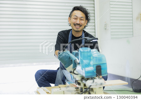 Craftsman working with an electric circular saw 130040394