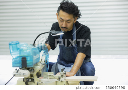 Craftsman working with an electric circular saw 130040398