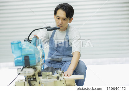 Craftsman working with an electric circular saw 130040452