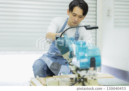 Craftsman working with an electric circular saw 130040453