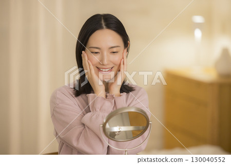 A woman doing skin care at night in her bedroom A woman doing skin care at night in her bedroom 130040552