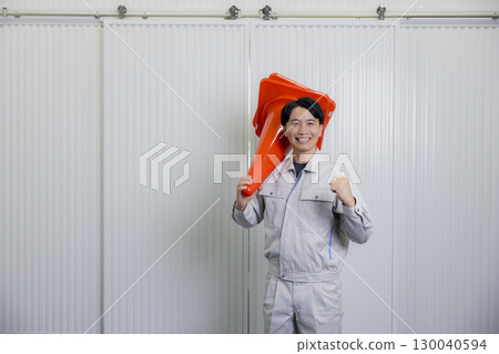Man in work clothes holding a pylon Man in work clothes holding a pylon 130040594