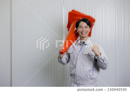Man in work clothes holding a pylon 130040595