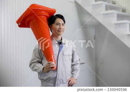 Man in work clothes holding a pylon 130040596
