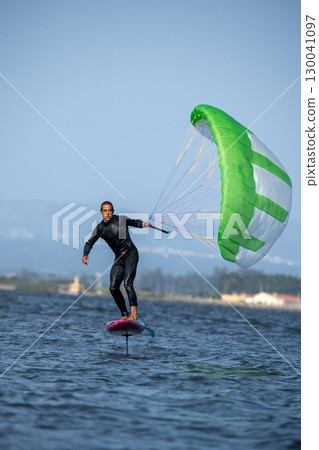 A middle-aged man in a wetsuit on a foil board glides across the water's surface A middle-aged man in a wetsuit on a foil board glides across the water's surface 130041097