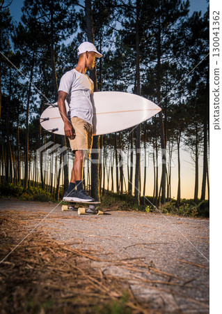 Surf skater rolling by the pine forest at sunset Surf skater rolling by the pine forest at sunset 130041362