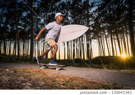 Surf skater rolling by the pine forest at sunset Surf skater rolling by the pine forest at sunset 130041363