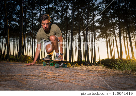 Surf skater rolling by the pine forest at sunset Surf skater rolling by the pine forest at sunset 130041419
