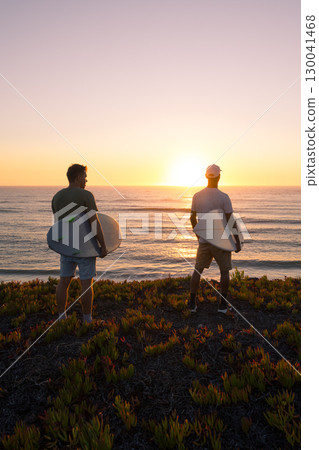 Surfers watching the waves at sunset 130041468