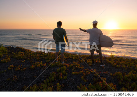 Surfers watching the waves at sunset 130041469