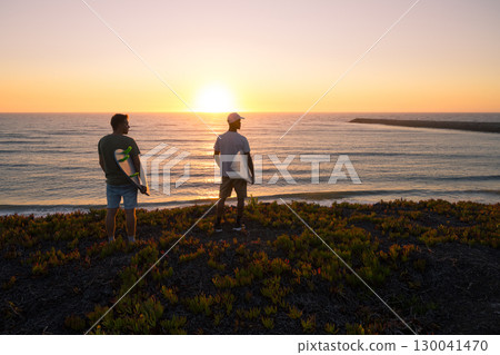 Surfers watching the waves at sunset 130041470